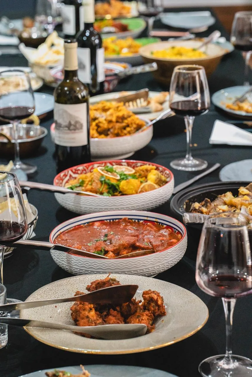 Mesa compartilhada com pratos Cape Malay, vinho e lugares ocupados